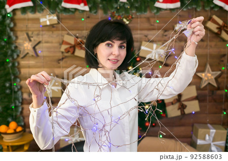 Woman with a New Year's garland in her hands, waiting for Christmas 92588603