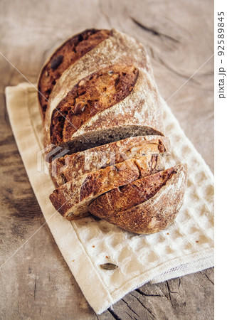 Brown fresh bread with seeds are cut into pieces on old wood background. Top view, copy space 92589845