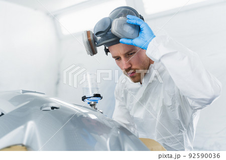 Young male car painter checks the quality of painting. Car service worker at work Young male car painter checks the quality of painting. Car service worker at work 92590036