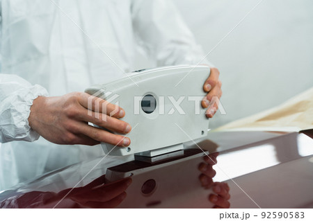 Close-up view of a auto painter determining the exact shade of a car's color using an electronic scanner Close-up view of a auto painter determining the exact shade of a car's color using an electronic scanner 92590583