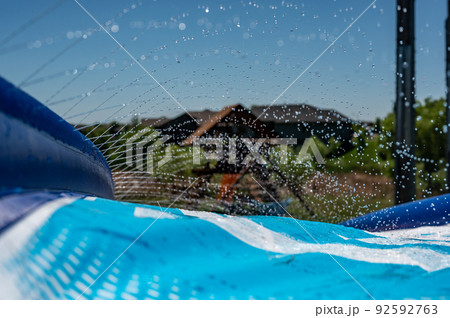 Selective focus on jets of droplets shooting out across a water slide Selective focus on jets of droplets shooting out across a water slide 92592763