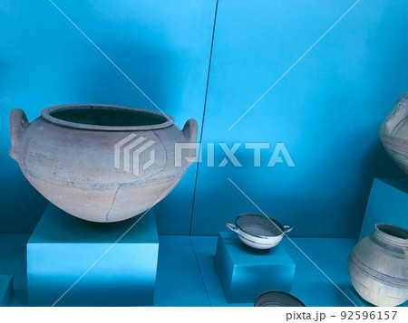 Museum piece. ancient dishes on a blue pedestal. exhibition samples. clay pots made by the hands of ancient people, with cracks and scuffs 92596157