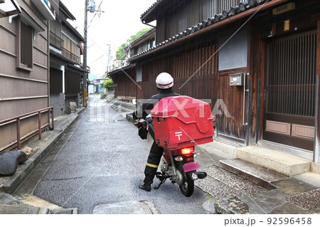 雨中の女性郵便配達員さん 92596458