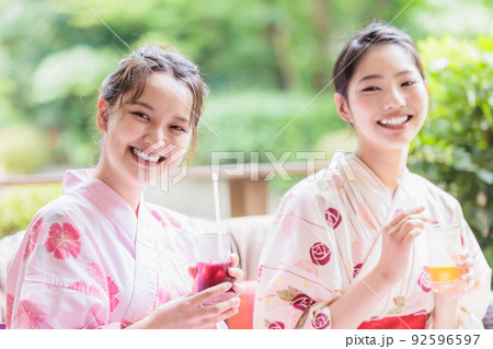 テラスでジュースを飲のんで仲良く談笑する女性 92596597
