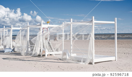 Beach bungalows by the sea on a clear sunny windy day. Vacation and tourism concept Beach bungalows by the sea on a clear sunny windy day. Vacation and tourism concept 92596718