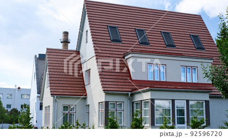 A private house of two floors with triangular roof and an area near the house against a blue sky A private house of two floors with triangular roof and an area near the house against a blue sky 92596720