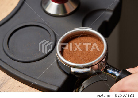 Asian man coffee shop part time employee brew hot coffee in coffee machine. Male barista hand making espresso from ground coffee maker at modern cafe. Small business and part time job working concept. 92597231