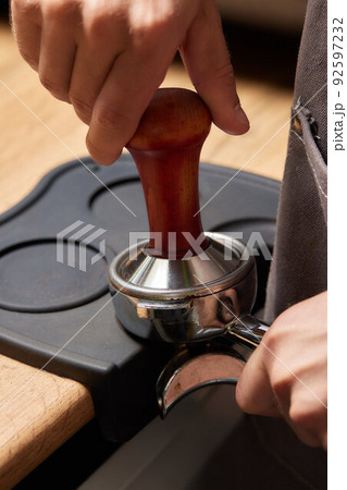 Asian man coffee shop part time employee brew hot coffee in coffee machine. Male barista hand making espresso from ground coffee maker at modern cafe. Small business and part time job working concept. 92597232