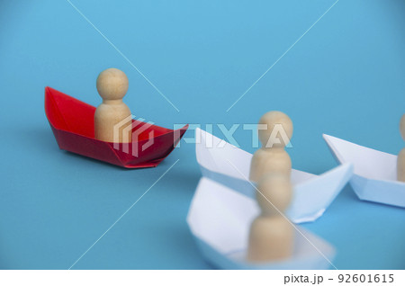 Leadership Concept - Wooden figure on red paper ship origami leading the rest of the figure on white paper ship. 92601615