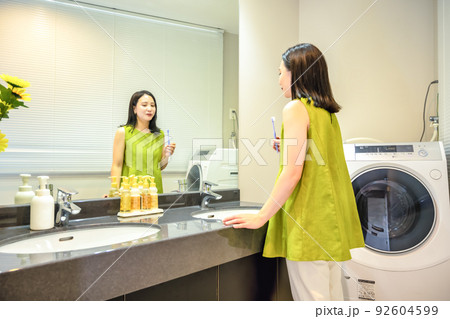 ダブルシンクの脱衣所で歯磨きをする若い女性 92604599