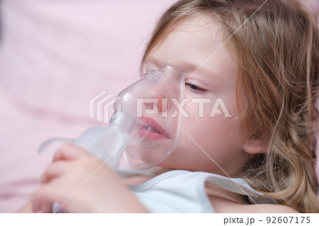 Little baby girl with oxygen mask lying on hospital bed or at home 92607175