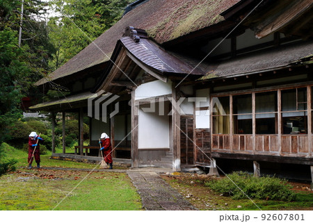 かやぶき屋根の社務所庭掃除風景 92607801