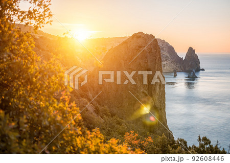 Selective focus. Autumn foliage and sea landscape with warm sunset light over a rocky coastline Calm sea on a background of rocky shores. The concept of an ideal place for autumn travel and relaxation 92608446