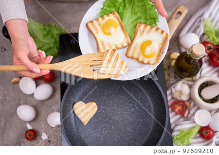 Fried egg Toasts with heart shaped holes on frying pan 92609210