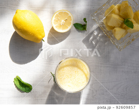 A glass of pineapple smoothie on wooden background with rays of the sun. Helthy food. 92609857