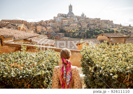 woman walks on background of cityscape of Siena old town in Italy 92611110