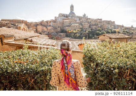 woman walks on background of cityscape of Siena old town in Italy 92611114