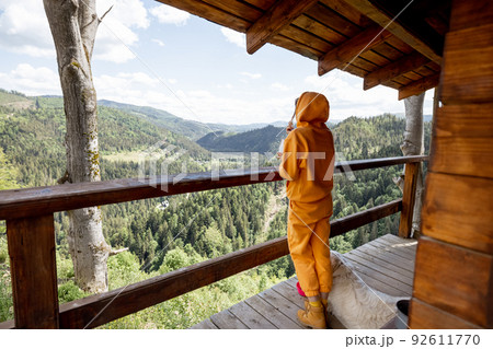 Woman enjoys great view on mountains from nature house Woman enjoys great view on mountains from nature house 92611770