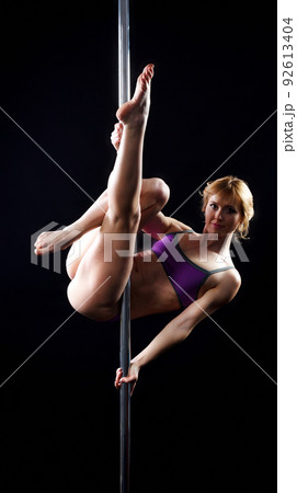 The strong and graceful young girl performing acrobatic exercises on pylon 92613404