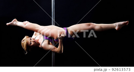 The strong and graceful young girl performing acrobatic exercises on pylon The strong and graceful young girl performing acrobatic exercises on pylon 92613573