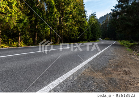 Empty rural highway alpine mountan road at high coniferous pine tree bottom POV. Scenic abstract forest roadway landscape foggy spring morning. European nature travel car concept. Nobody car scene Empty rural highway alpine mountan road at high coniferous pine tree bottom POV. Scenic abstract forest roadway landscape foggy spring morning. European nature travel car concept. Nobody car scene 92613922