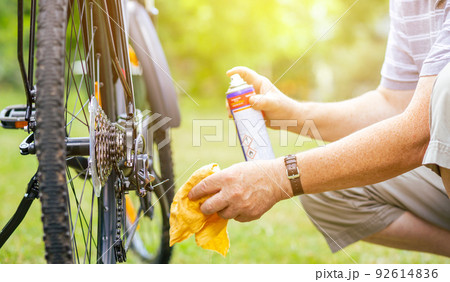 Senior man doing maintenance for his bicycle during summer time, oiling his chain of the bike, healthy lifestyle 92614836