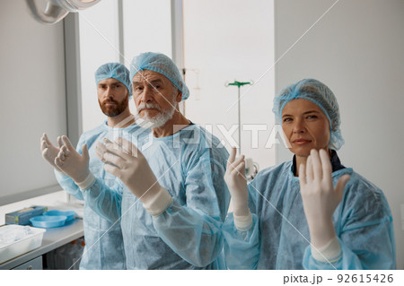 Team of surgeons in the operating room ready for surgery in clinic looking at camera Team of surgeons in the operating room ready for surgery in clinic looking at camera 92615426