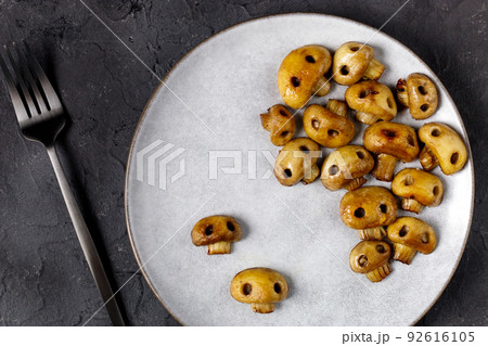 Round plate with mushrooms in the form of skulls and fork on white table. Edible Halloween Concept 92616105