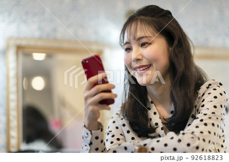 スマートフォンの画面を見る笑顔の若い女性 スマートフォンの画面を見る笑顔の若い女性 92618823