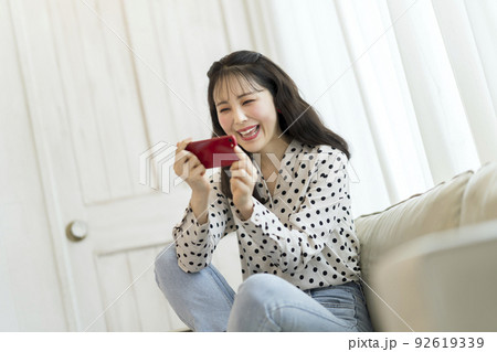 スマートフォンを見る笑顔の若い女性 スマートフォンを見る笑顔の若い女性 92619339