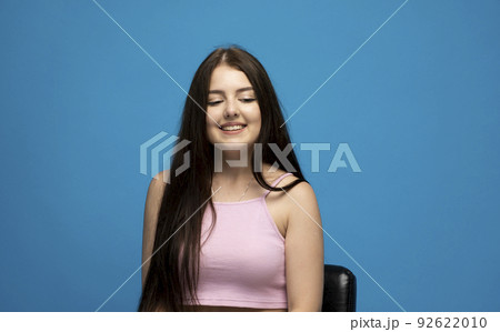 Beautiful cute gergerous brunette girl with long hair in a casual pink t-shirt looking down. 92622010