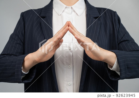 Business woman in a suit holding her hands in the shape of a house. Business woman in a suit holding her hands in the shape of a house. 92623945