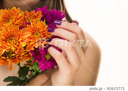 Skincare cosmetic. Unrecognizable latin woman manicure pink nails. Autumn chrysanthemum blossom  92625772