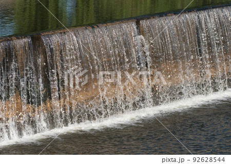 The water flow pass the weir from upper level to lower level.Water flow very fast in rainy season.Selective focus. 92628544