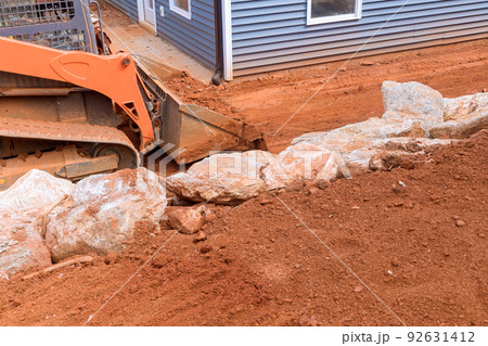 During the landscaping work on construction site, a bulldozer performs work with earth soil 92631412