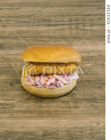 Single fish burger with coleslaw on wooden table Single fish burger with coleslaw on wooden table 92632569
