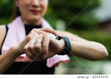 Unrecognizable sporty women in sports wear raise hand and use finger to adjust setting application in smartwatch on wrist to checking result after workout or exercise. Concept of good health care 92634023