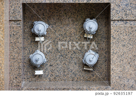 Fire hydrants embedded in the granite wall of the building. 92635197
