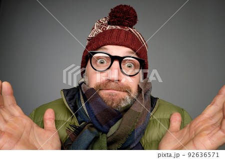 Portrait of confused mature man in warm winter clothes standing over gray background gesturing with hands. Portrait of confused mature man in warm winter clothes standing over gray background gesturing with hands. 92636571