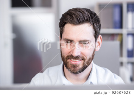 Close-up portrait of businessman at work looking at monitor working in office Close-up portrait of businessman at work looking at monitor working in office 92637628