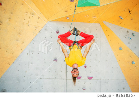 A man hangs upside down in a lotus position on a climbing wall 92638257