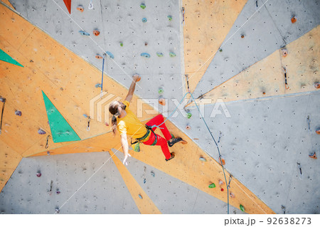 Sportsman climber moving up on steep rock, climbing on artificial wall. 92638273