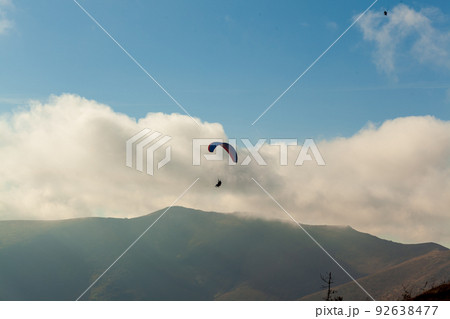 Paraglider flying over clouds in summer day Paraglider flying over clouds in summer day 92638477