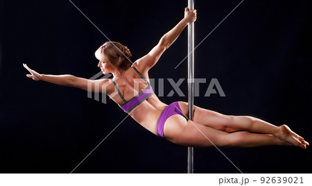 The strong and graceful young girl performing acrobatic exercises on pylon The strong and graceful young girl performing acrobatic exercises on pylon 92639021