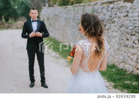 Happy stylish smiling couple walking in Tuscany, Italy on their wedding day. The bride and groom walk down the street by the hands. A stylish young couple walks. Husband and wife communicate nicely 92639290