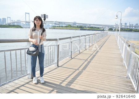 海辺で自撮り棒を使ってスマホで撮影をする女性 海辺で自撮り棒を使ってスマホで撮影をする女性 92641640