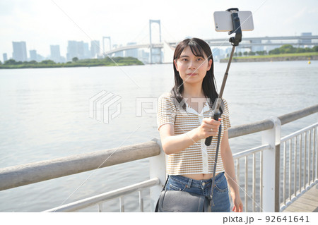 海辺で自撮り棒を使ってスマホで撮影をする女性 海辺で自撮り棒を使ってスマホで撮影をする女性 92641641