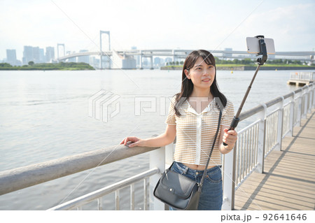 海辺で自撮り棒を使ってスマホで撮影をする女性 海辺で自撮り棒を使ってスマホで撮影をする女性 92641646