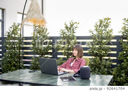 Woman works on laptop online in the garden outdoors 92641704