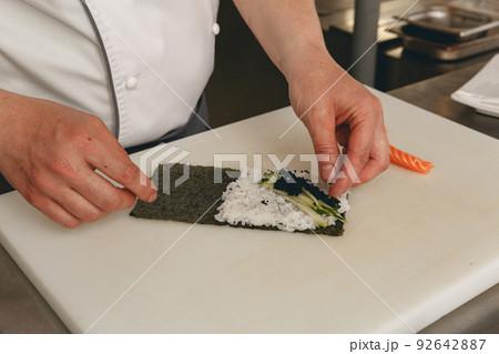 Chef hands cooking sushi with rice, salmon and nori on kitchen of japanese restaurant Chef hands cooking sushi with rice, salmon and nori on kitchen of japanese restaurant 92642887